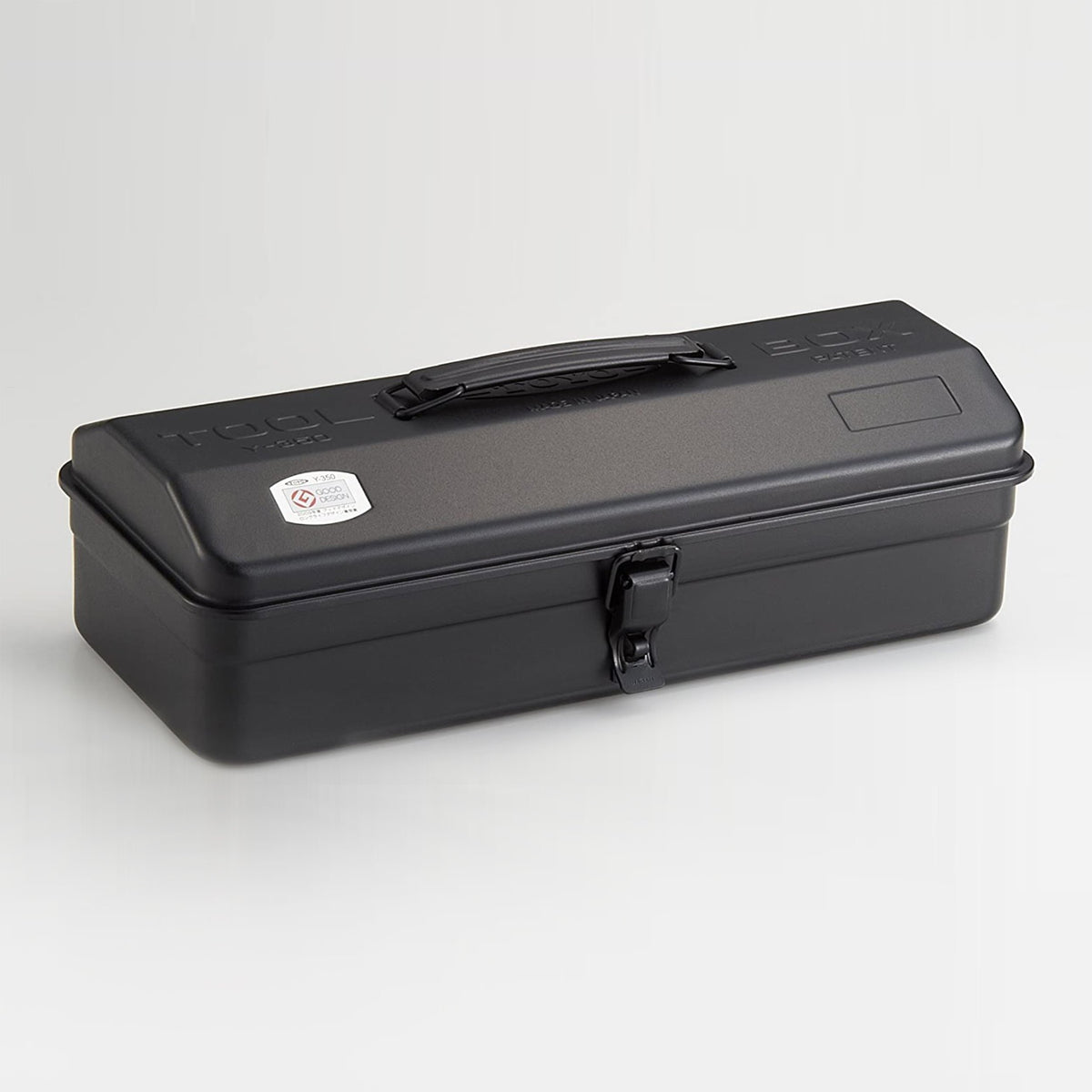 Black Toyo Y-350 steel toolbox with matte finish, elongated rectangular shape, integrated top handle, and single front latch, shown closed on a light neutral studio background.
