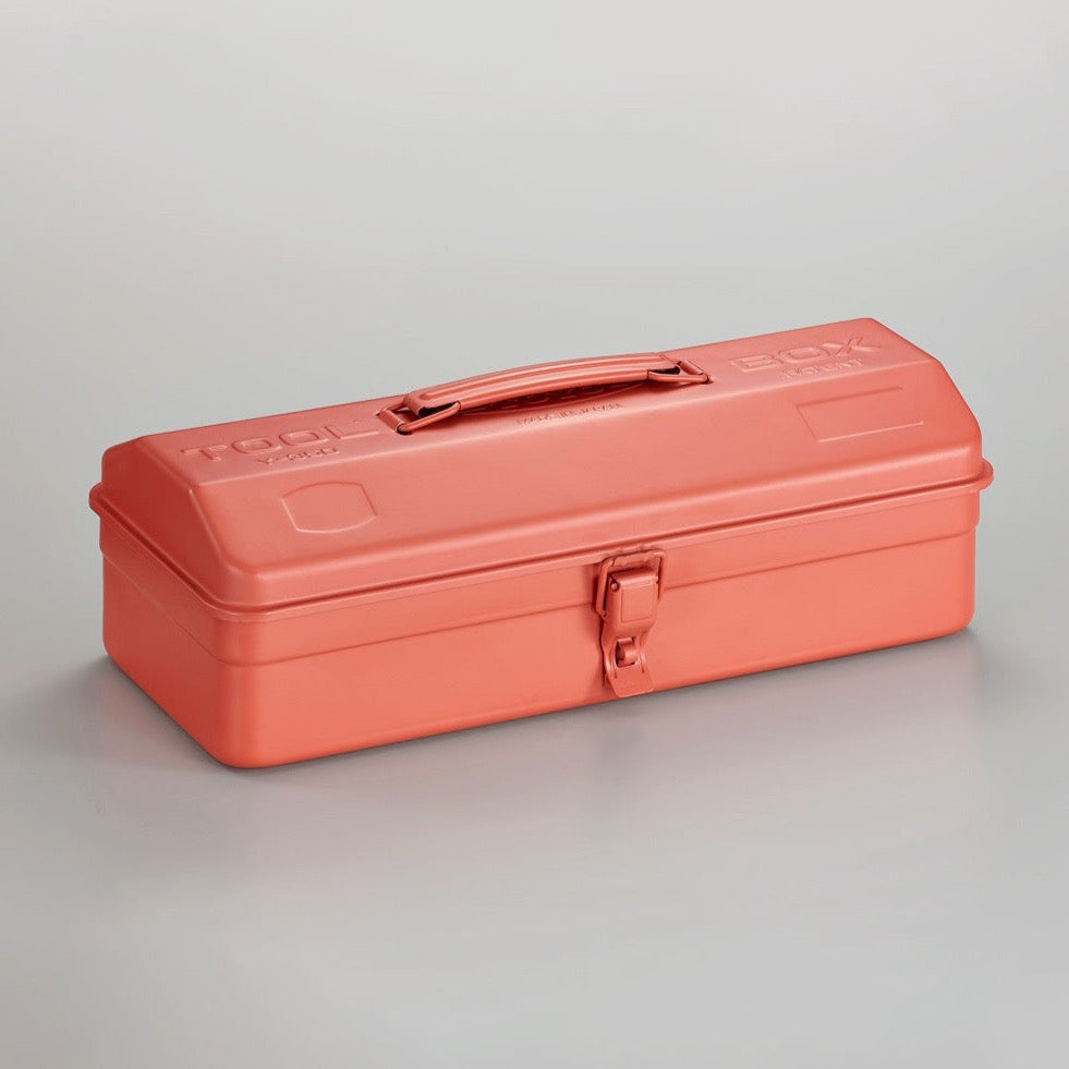 Coral pink Toyo Y-350 steel toolbox with smooth matte finish, rounded rectangular lid, integrated top handle, and single front latch, shown closed on a neutral gray studio background.