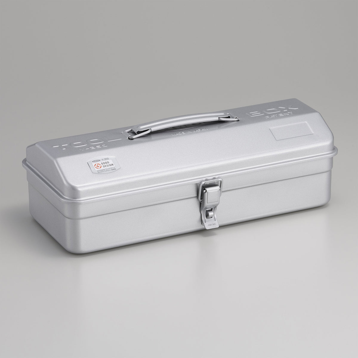 Silver Toyo Y-350 steel toolbox with matte metallic finish, rounded rectangular lid, integrated top handle, and single front latch, shown closed on a neutral gray studio background.